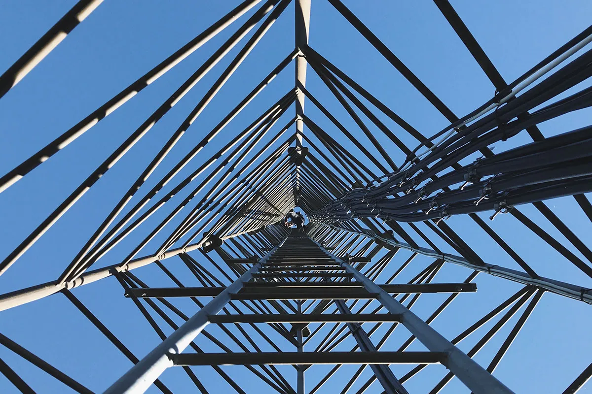 Steel lattice tower seen from below against a blue sky